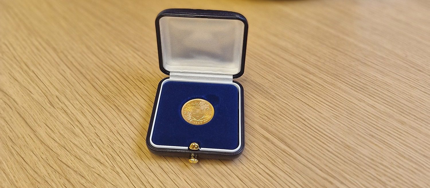 Gold coin in a blue velvet presentation case on a wooden surface