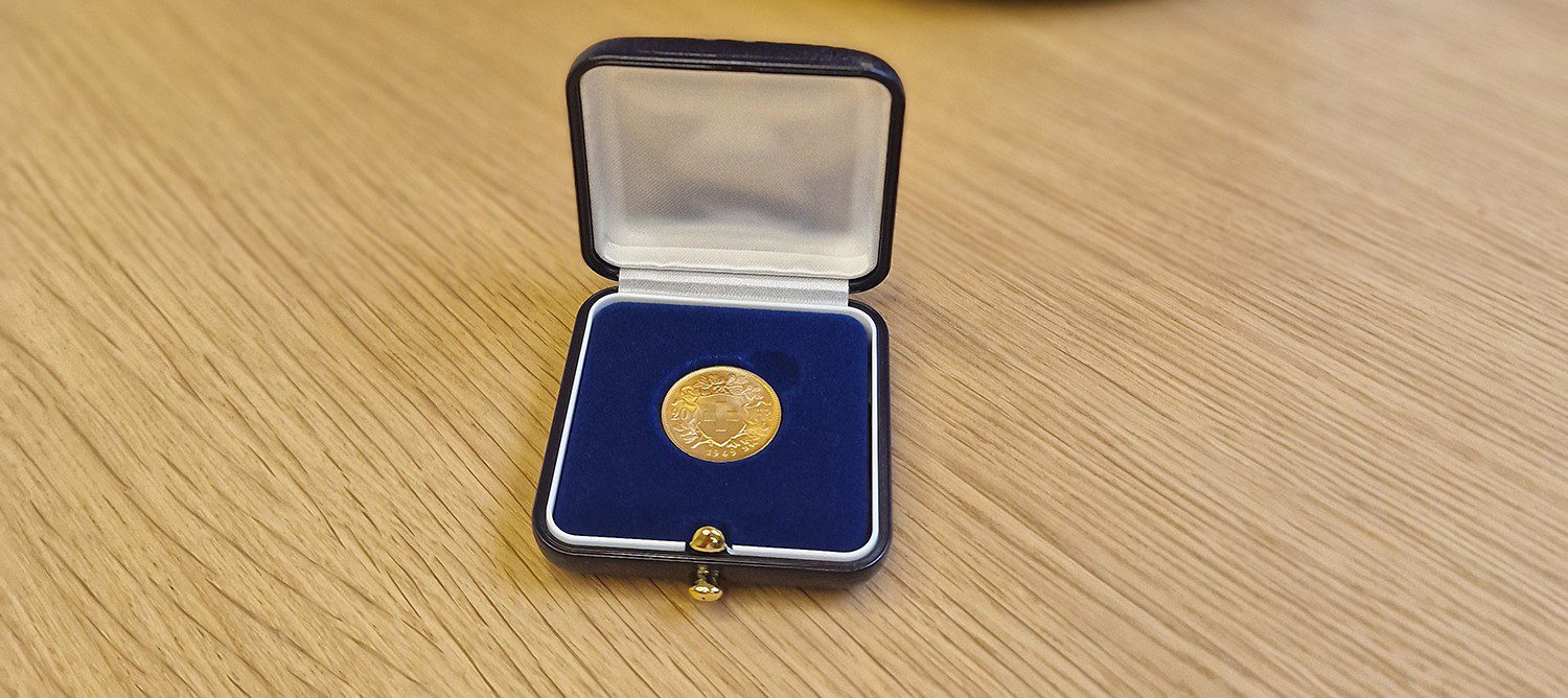 Gold coin in a blue velvet presentation case on a wooden surface